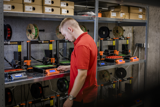Mann steht vor Regal mit 3D Druckern.jpg